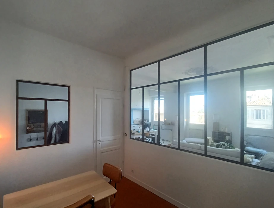 Intérieur moderne avec baies vitrées, homme en blanc travaillant sur terrasse extérieure