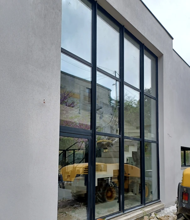 Intérieur moderne en cours de finition avec murs blancs lisses et fenêtres à châssis noir