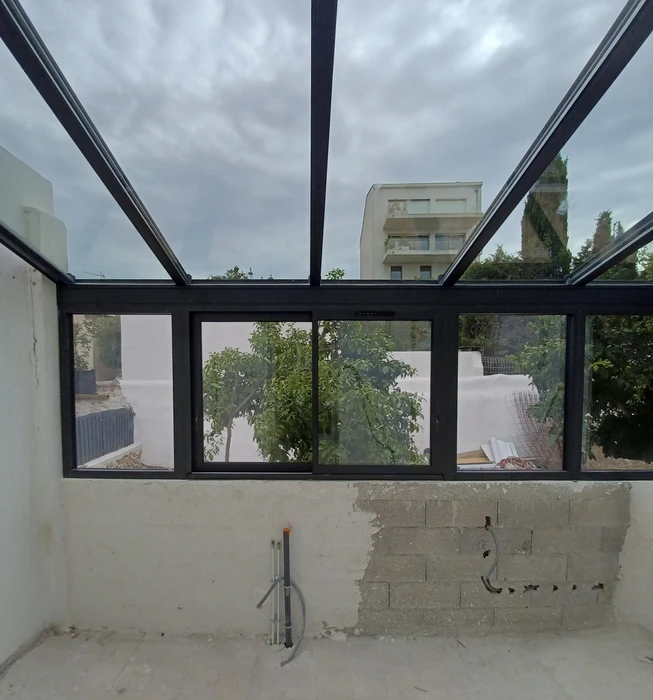 Chantier de construction d'une véranda ou extension avec structure métallique noire en cours d'installation